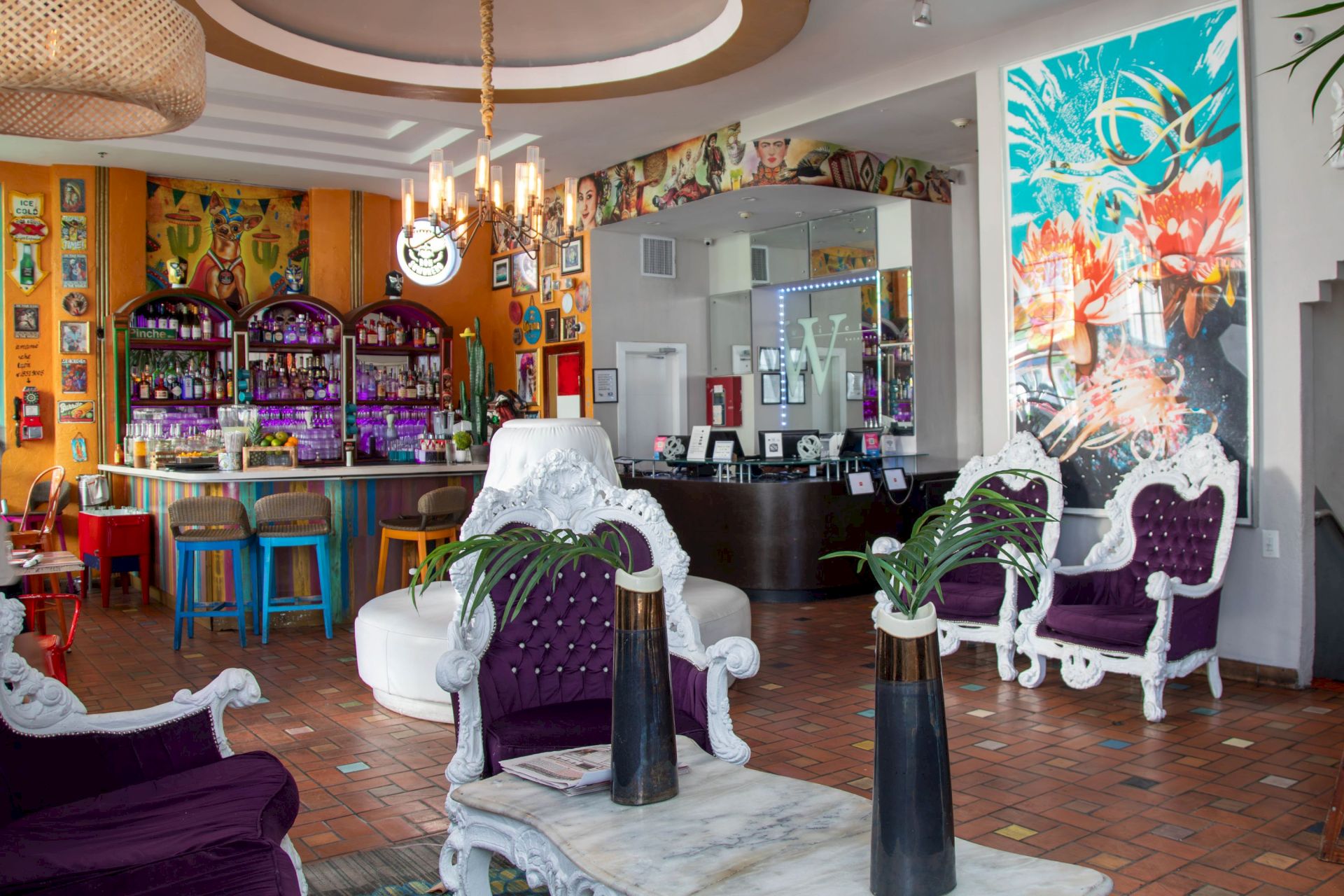 A colorful, retro-style cafe or lounge with vibrant purple chairs, white ornate furniture, tropical wall art, a bar area, and plants, creating a lively, eclectic vibe.