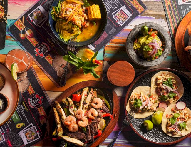 Delicious tapas and tacos spread across colorful plates, featuring shrimp skewers, grilled meats, fresh tortillas, and vibrant garnishes, perfect for sharing.